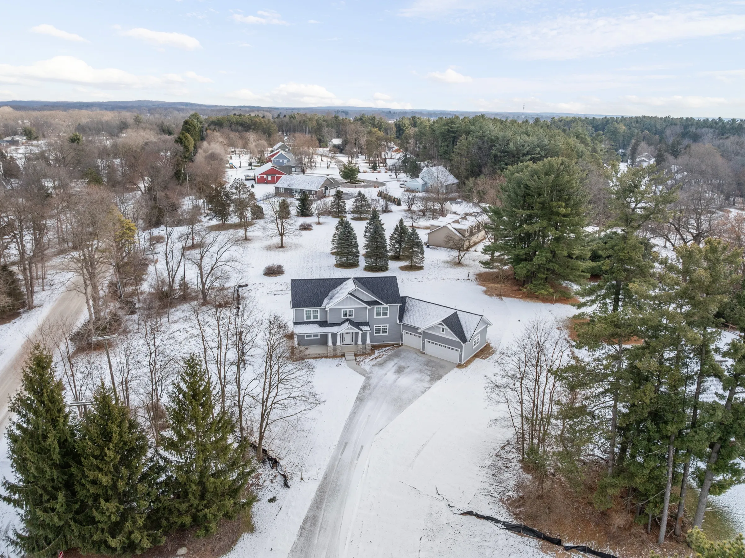 Aerial view of the house on its snowy lot, ringed by mature pines and the neighboring homes on the court.