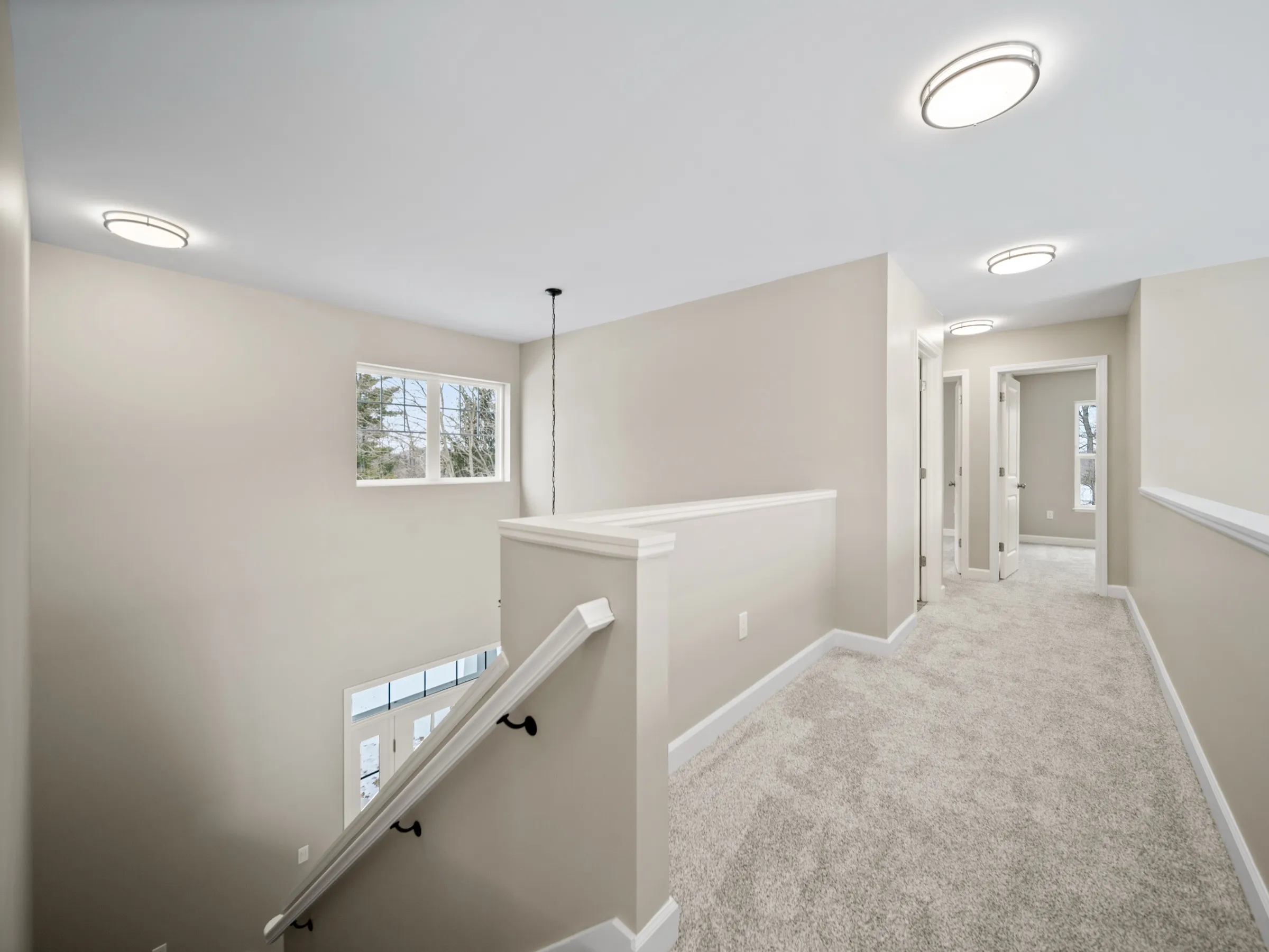 Second-floor landing with a white railing over the entry, bedroom doors off the carpeted hall.