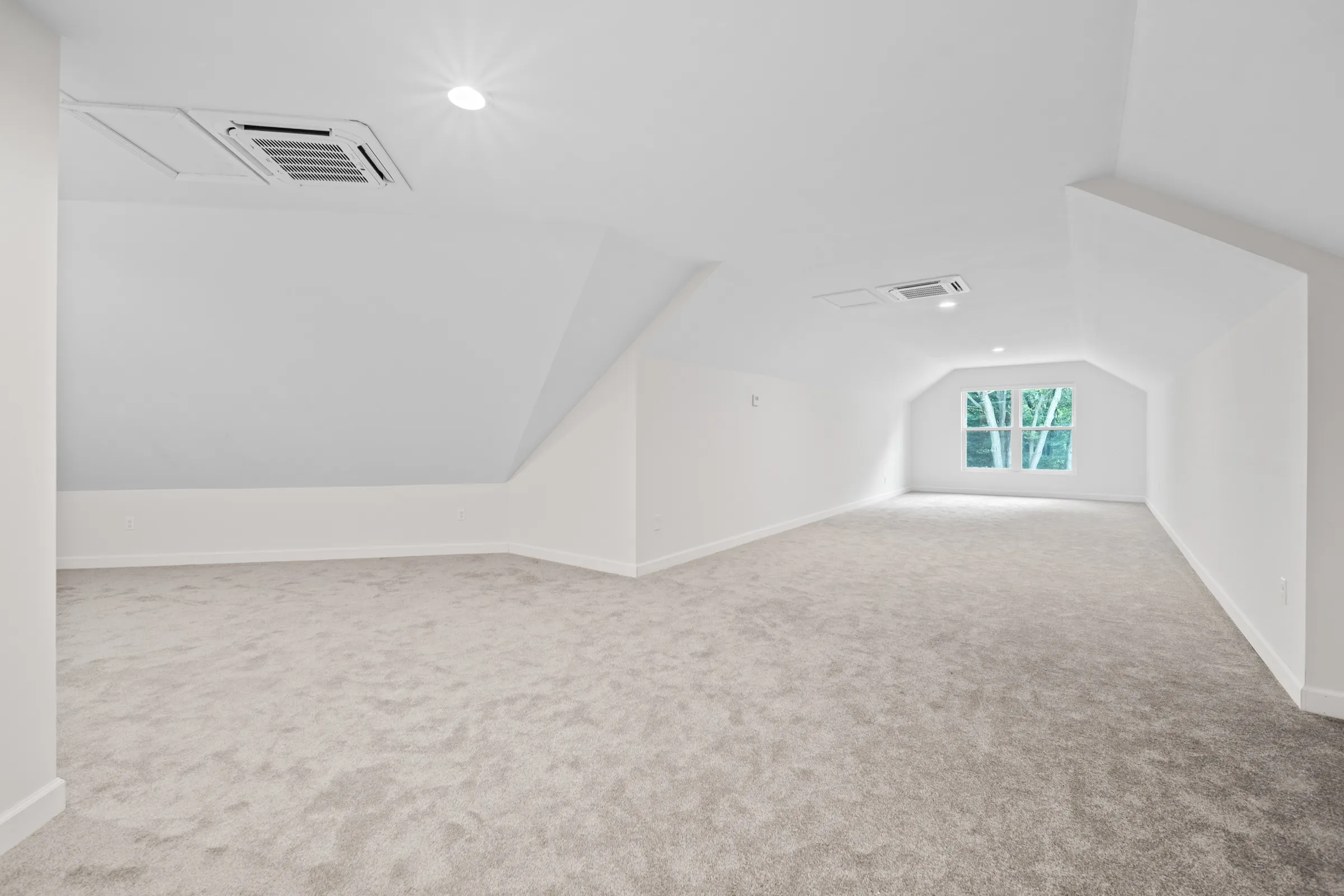 Carpeted bonus room over the garage with sloped ceilings and a dormer window.